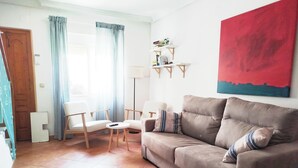 Un salon comprenant un canapé, deux fauteuils, une petite table, une lampe et une bibliothèque.