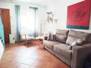 A living room with a sofa, two chairs, a small table, a lamp, and a bookshelf. - Vrbo Property (Salobreña)