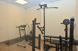 A gym with exercise equipment including a treadmill, weight bench, and various weightlifting stations. - LUXURY SWIMMING POOL HOTEL TF RESORT (Calangute)