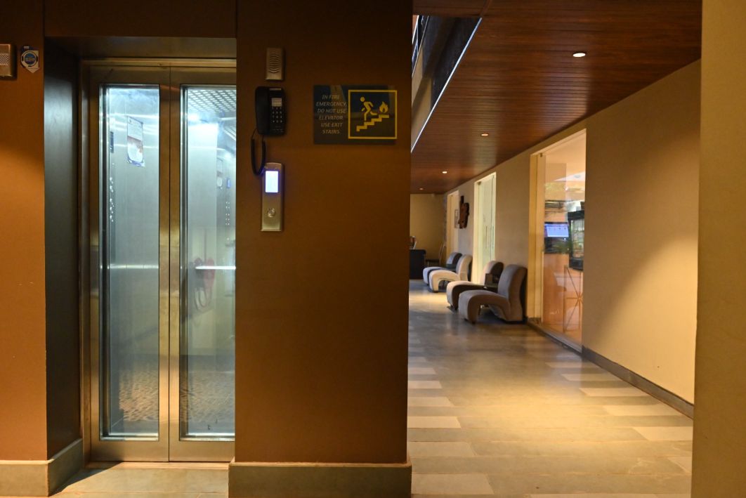 Un ascensor con puertas de vidrio, un teléfono e instrucciones de emergencia en la pared.