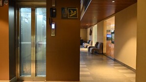 Un ascensor con puertas de vidrio, un teléfono e instrucciones de emergencia en la pared.