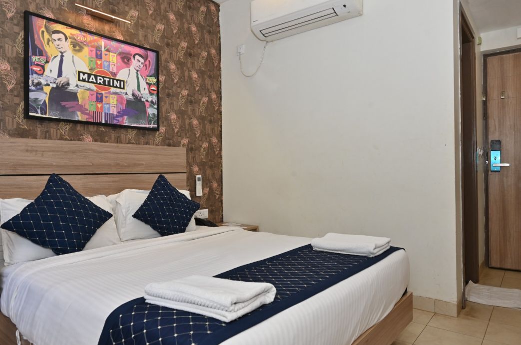 Een hotelkamer met een bed, een wandairconditioner en een deur.