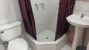 Ein Badezimmer mit einer weißen Toilette, einer Dusche mit Glastür und einem weißen Waschbecken.