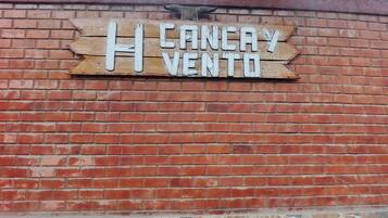 Un muro de ladrillo con un letrero de madera que dice 'CANELA VENTO'.