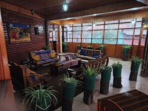 A room with a brick wall mural, wooden furniture, and large windows.
