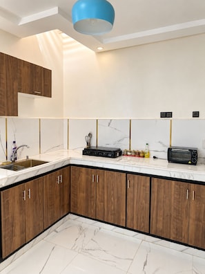 A modern kitchen with wooden cabinets, a marble countertop, and a built-in oven.