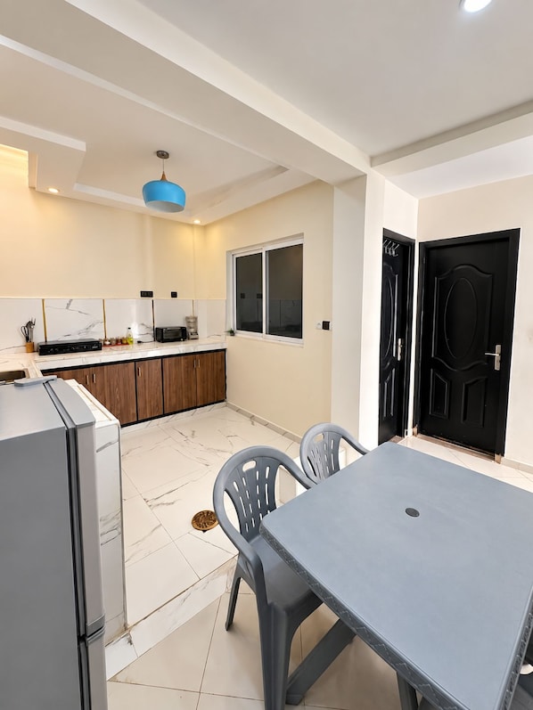 A modern kitchen with a dining area, featuring a refrigerator, stove, and cabinets.