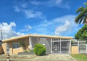 A residential building with a gated entrance, a small garden, and a clear blue sky. - San Juan: Cerca de aeropuerto, playas y zonas turísticas - 3 hab. 2 baños (San Juan)