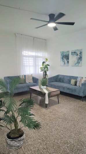A living room with two sofas, a coffee table, a ceiling fan, and a potted plant. - San Juan: Cerca de aeropuerto, playas y zonas turísticas - 3 hab. 2 baños (San Juan)