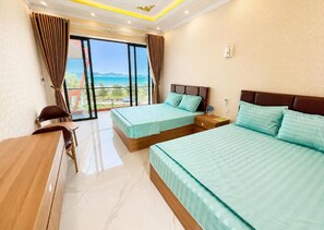 Ein Hotelzimmer mit zwei Betten, einem Schreibtisch und Meerblick.