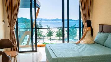 Un dormitorio con una cama grande, vista al mar y un balcón.
