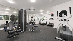 A gym with cardio machines, weightlifting equipment, and a mirrored wall. - The Ember | 2BR|2BA|Pool, Gym, Sauna + Parking | Boutique Stay near Sydney CBD (Waterloo)