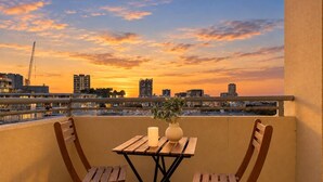 An outdoor balcony with a wooden table and chairs, a candle, and a vase with plants. - The Ember | 2BR|2BA|Pool, Gym, Sauna + Parking | Boutique Stay near Sydney CBD (Waterloo)