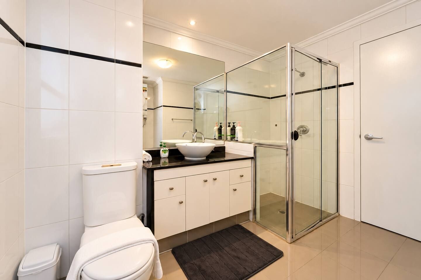 A modern bathroom with a toilet, sink, and glass shower enclosure.