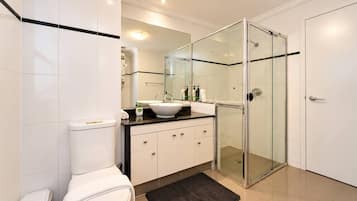 A modern bathroom with a toilet, sink, and glass shower enclosure.