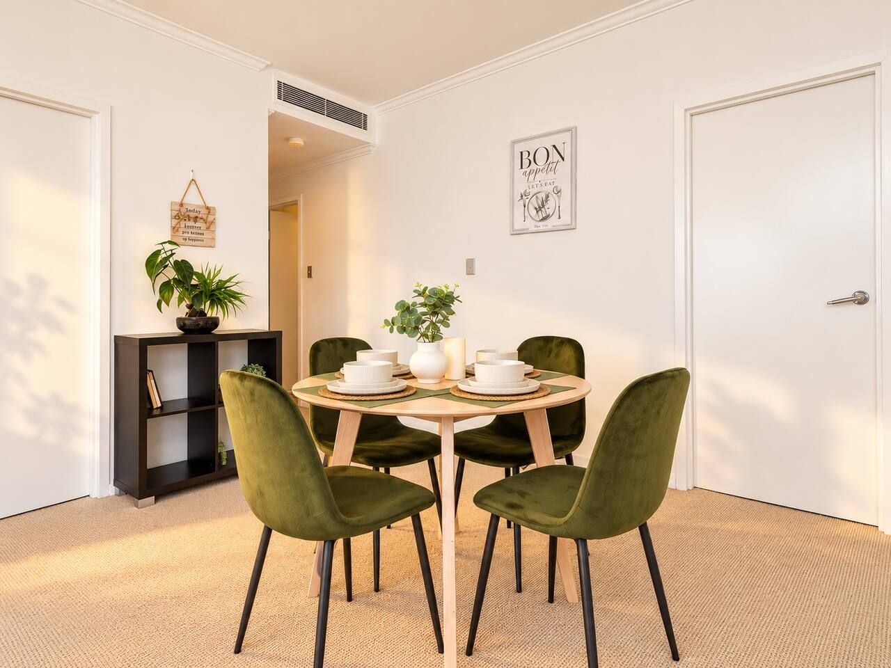 A dining area with a round table, four chairs, and a small potted plant.