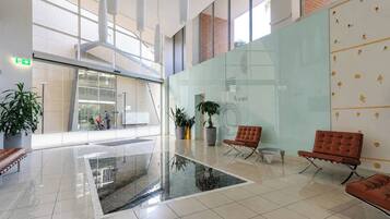 A spacious lobby with a glass partition, modern seating, and a clear view of the outside.