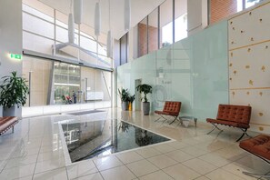 A spacious lobby with a glass partition, modern seating, and a clear view of the outside. - The Ember | 2BR|2BA|Pool, Gym, Sauna + Parking | Boutique Stay near Sydney CBD (Waterloo)