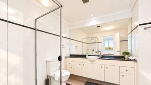 A modern bathroom with a glass shower enclosure, a toilet, a sink, and a mirror. - The Ember | 2BR|2BA|Pool, Gym, Sauna + Parking | Boutique Stay near Sydney CBD (Waterloo)