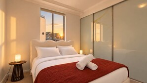 A hotel room with a large bed, a view of the city through a window, and a sliding door. - The Ember | 2BR|2BA|Pool, Gym, Sauna + Parking | Boutique Stay near Sydney CBD (Waterloo)