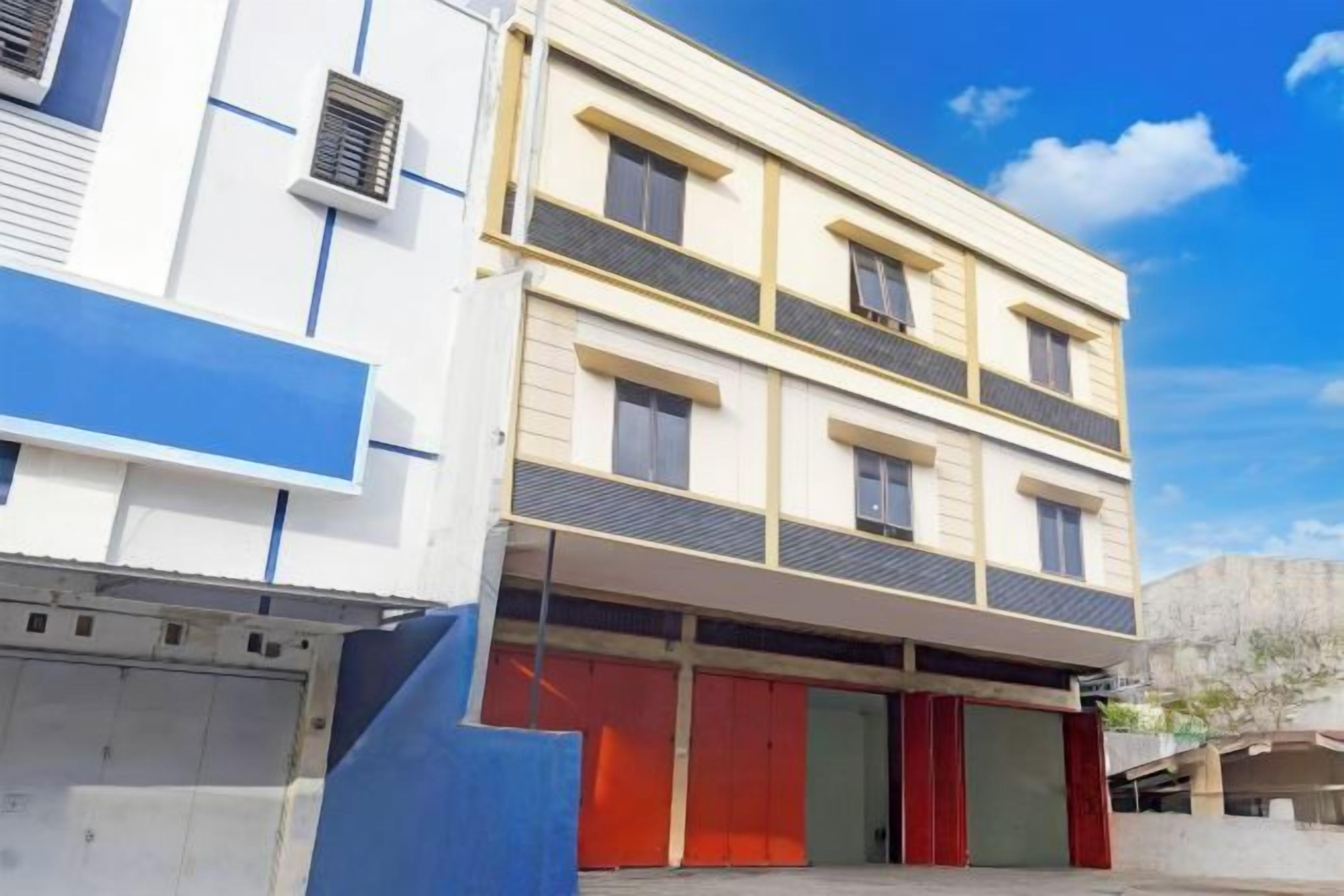Un edificio de varios pisos con fachada plana, amplios ventanales y un área de entrada cubierta.