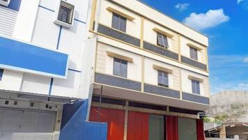 Un edificio de varios pisos con fachada plana, amplios ventanales y un área de entrada cubierta.