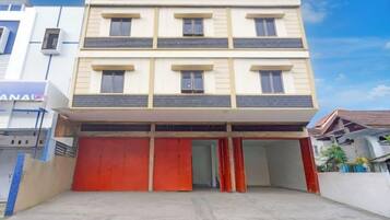 Un edificio de varios pisos con techo plano, puerta de garaje roja y entrada visible.