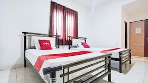 Un lit double avec une couvre-lit blanche et rouge, deux oreillers, une table de chevet et une fenêtre avec des rideaux.