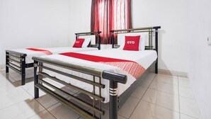 Un lit double avec un cadre en métal, deux oreillers et une couvre-lit rouge et blanche.