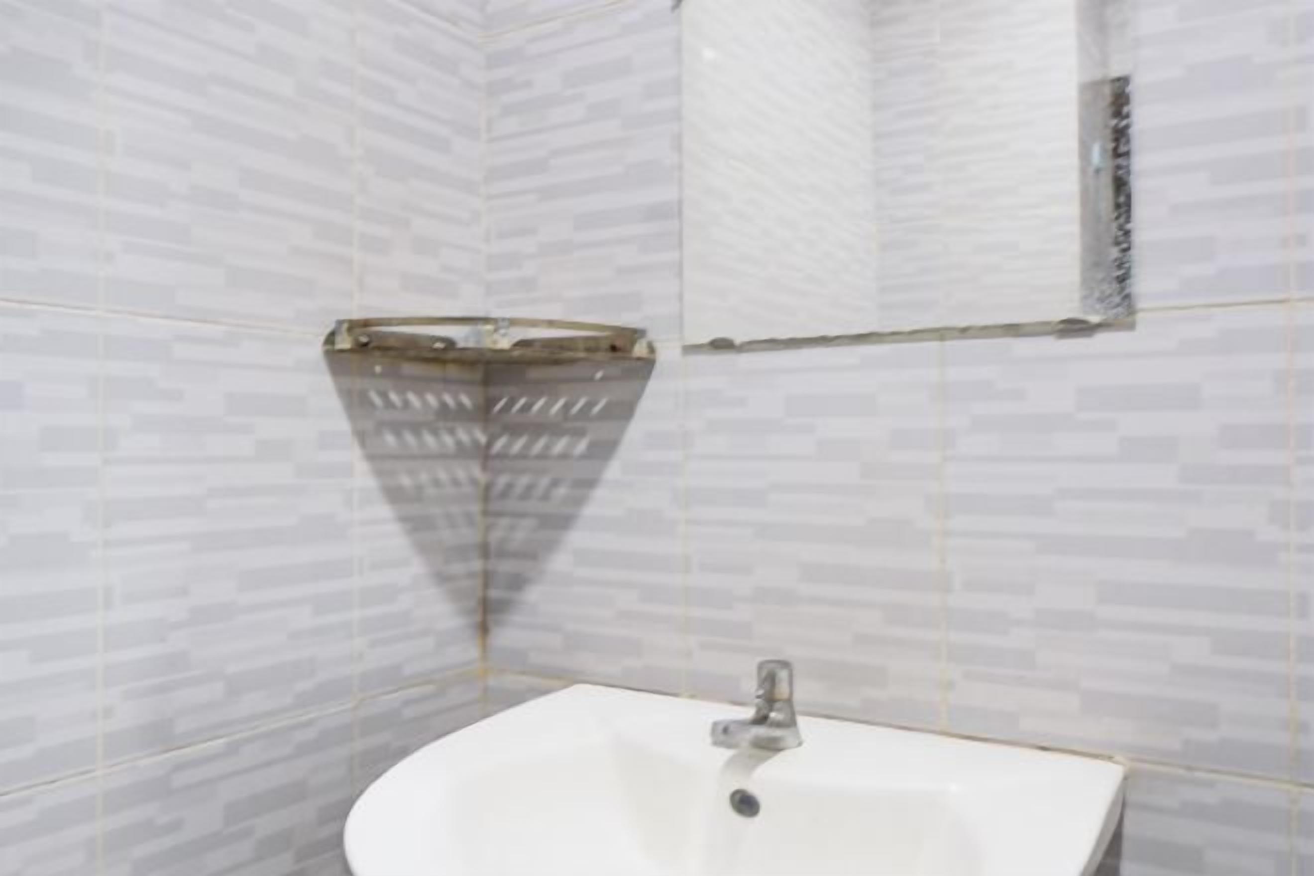 Un bagno con un lavandino bianco, pareti piastrellate e zona doccia.