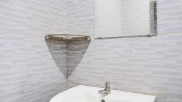 Un bagno con un lavandino bianco, pareti piastrellate e zona doccia.