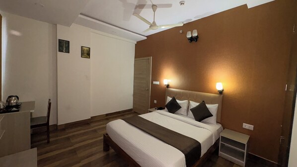 A hotel room with a bed, bedside tables, a desk, and a ceiling fan.