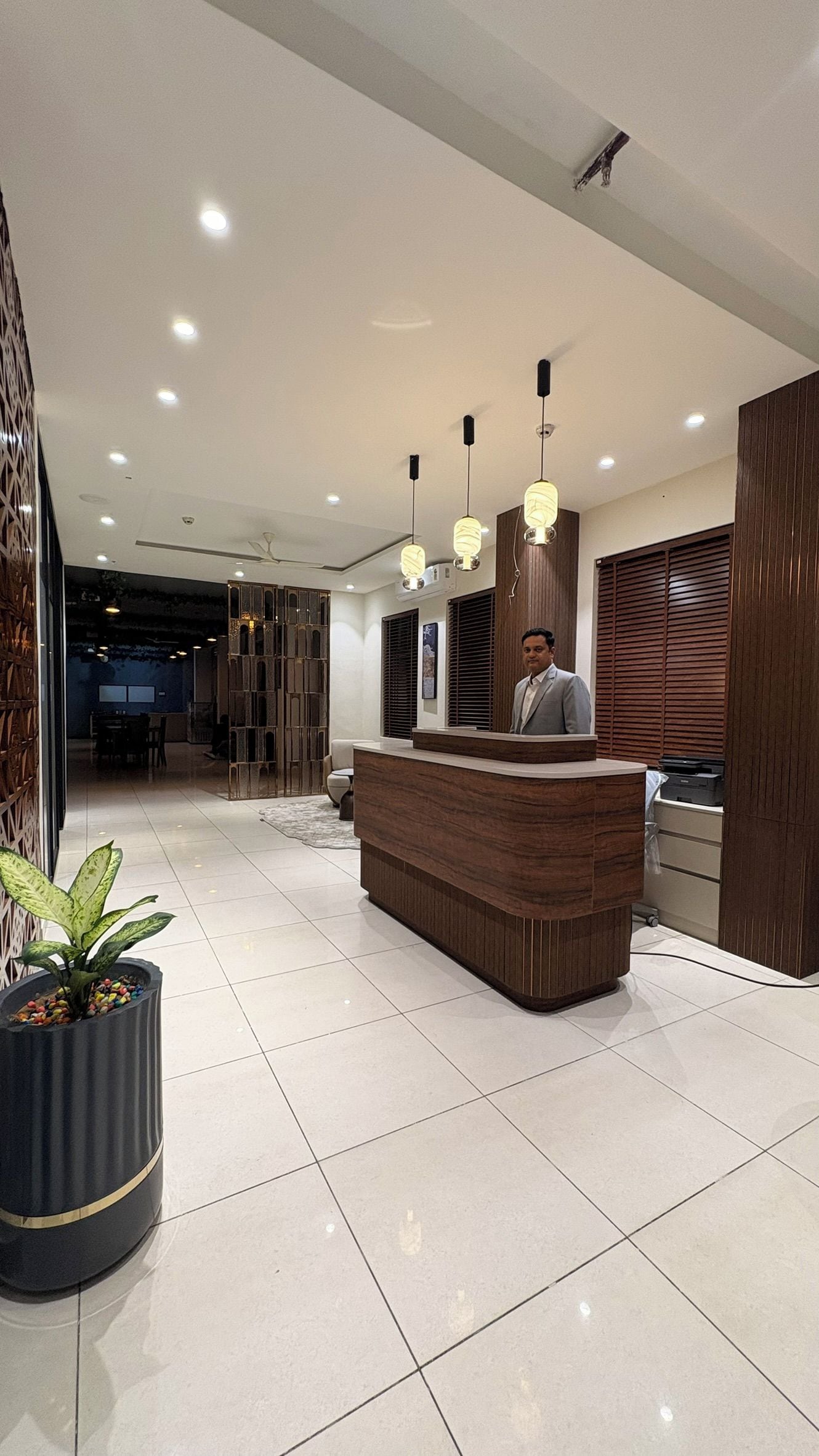 A hotel reception area with a reception desk, a potted plant, and a modern interior design.