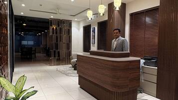 A hotel reception area with a reception desk, a potted plant, and a modern interior design.