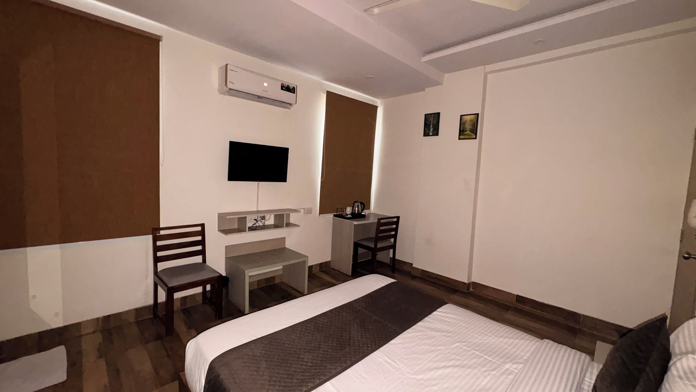 Een hotelkamer met een bed, bureau, stoel, televisie en een kledingkast.