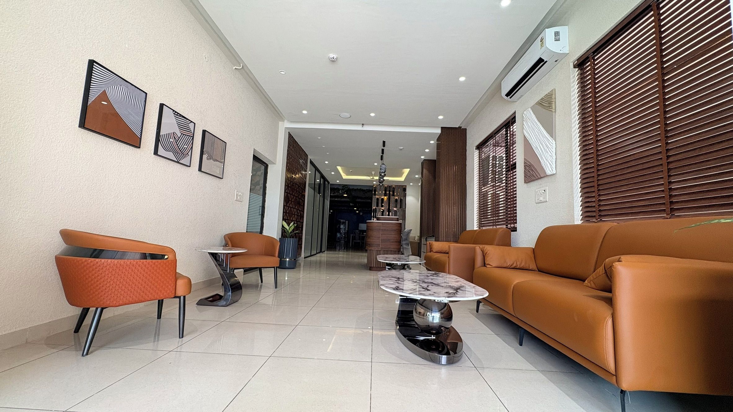 Un interior moderno con un sofá, sillas, una mesa de centro y obras de arte en las paredes.