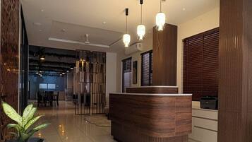 A reception area with a wooden reception desk, a potted plant, and a modern ceiling design.