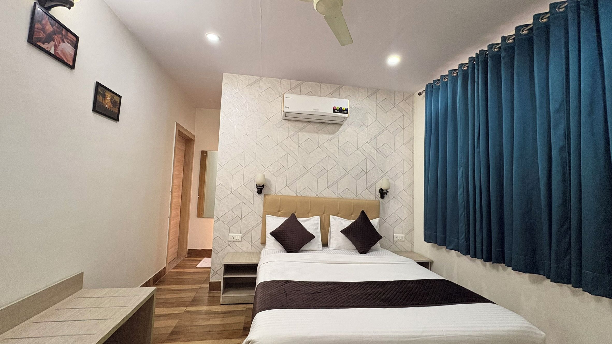A hotel room with a bed, a ceiling fan, an air conditioning unit, and a view of a blue curtain.