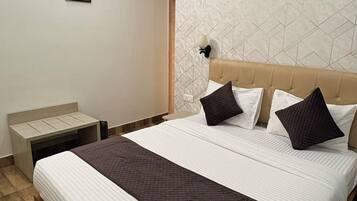 Habitación de hotel con cama, mesita de noche, ventilador de techo y aire acondicionado instalado en la pared.