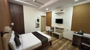 Ein Hotelzimmer mit Bett, Schreibtisch, Stuhl, Fernseher und Klimaanlage.