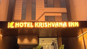 A hotel entrance with a sign reading 'HOTEL KRISHVANA INN' and a staircase leading up to the entrance.