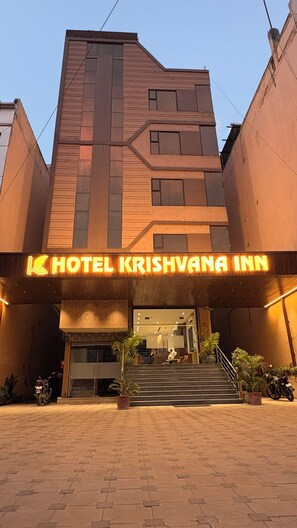 A hotel entrance with a sign reading 'HOTEL KRISHVANA INN' and a staircase leading up to the entrance.