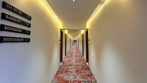 A hotel hallway with directional signs for rooms 211 to 222, a banquet, a restroom, and a restaurant. - Krishvana Inn (Jaipur)