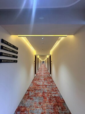 Un pasillo de hotel con indicaciones hacia habitaciones 211 a 222, un salón de banquetes, un baño y un restaurante.