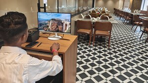 A hotel lobby with a large monitor displaying a scenic view, a reception desk, and a patterned floor. - Krishvana Inn (Jaipur)