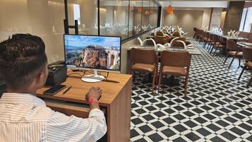 A hotel lobby with a large monitor displaying a scenic view, a reception desk, and a patterned floor.