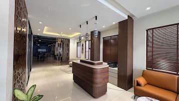A reception area with a wooden reception desk, a sofa, and a potted plant.