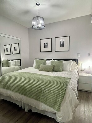A bedroom with a large bed, a bedside table, a nightstand, a mirror, and framed pictures on the wall. - Condo downtown toronto near Scotiabank arena (Toronto)