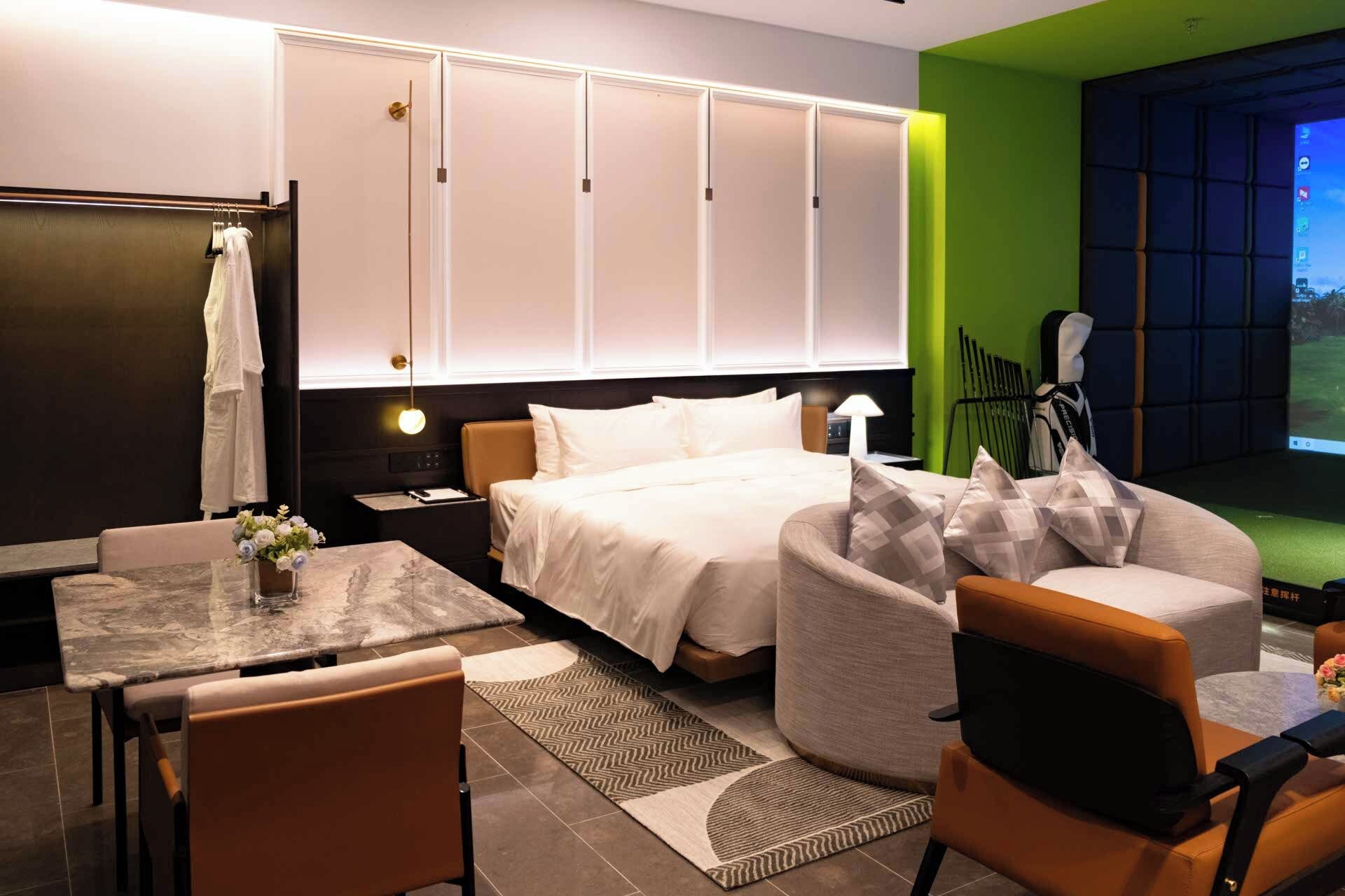Una habitación de hotel moderna con cama, zona de estar y televisor.
