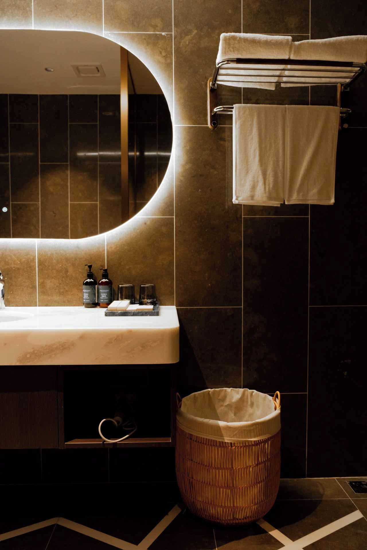 A bathroom with a vanity, a mirror, a towel rack, and a wicker basket.